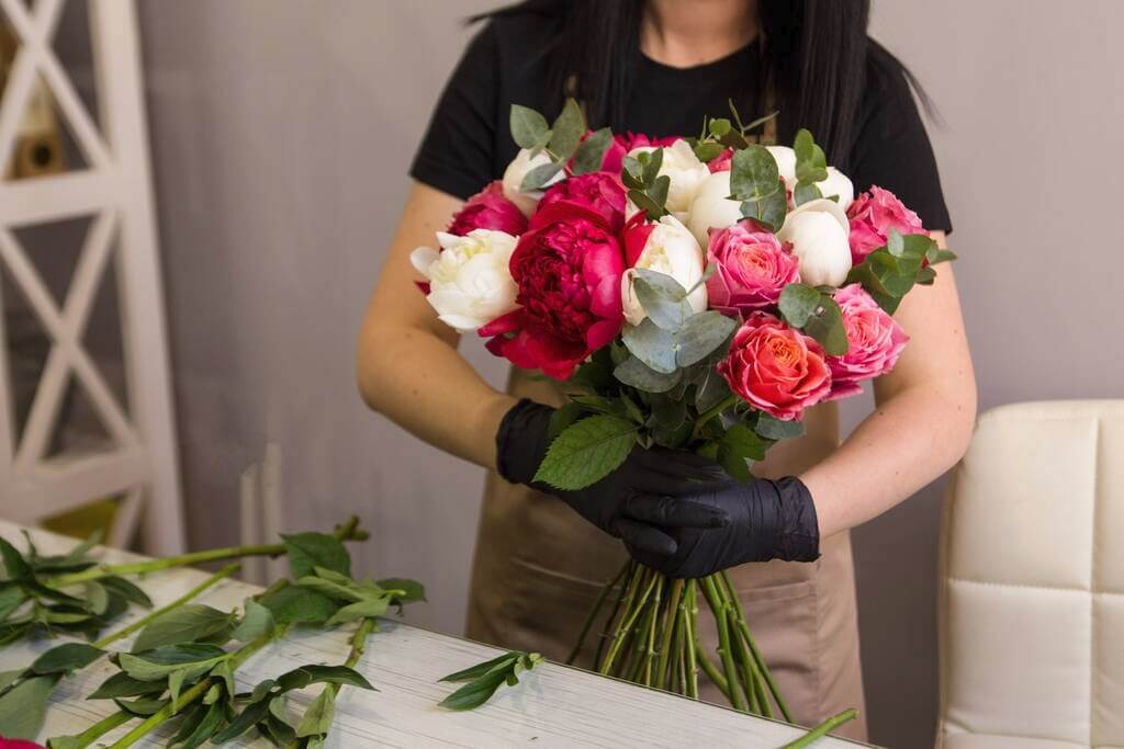 Florist wearing gloves holding a bunch of flowers