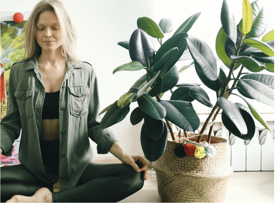 woman meditating next to a plant