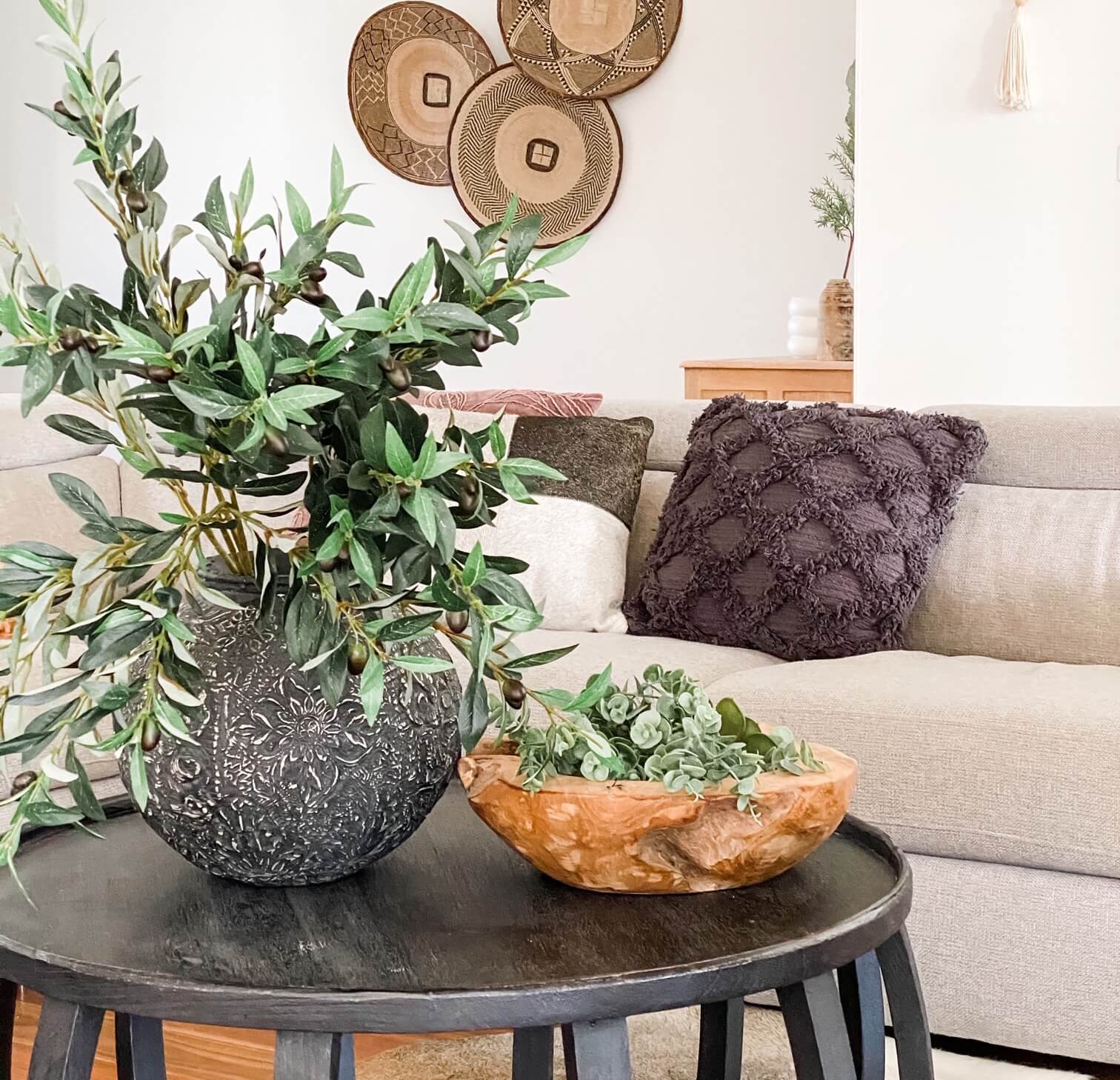 olive branches in a vase on a coffee table