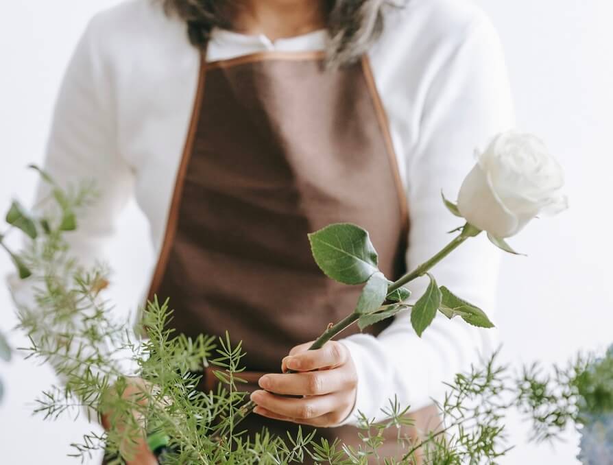 woman holding white rose stem